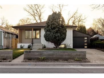 Charming ranch-style home features a brick exterior, a modern garage door, and a well-kept front yard at 4631 Zuni St, Denver, CO 80211