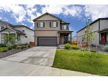 Charming two-story home with a well-maintained lawn, two-car garage, and neat landscaping at 933 Canal West Dr, Brighton, CO 80603