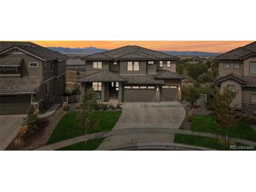 Beautiful two-story home with a three car garage, landscaped front yard and a stunning sunset at 16371 Jones Mountain Way, Broomfield, CO 80023
