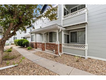 Charming townhome featuring a covered porch with brick accents and well-maintained landscaping at 12935 Lafayette St # B, Thornton, CO 80241