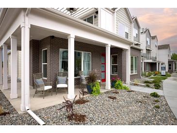 Inviting front porch of a townhouse featuring brick accents, a cozy seating area, and well-maintained landscaping at 888 S Valentia St # 103, Denver, CO 80247