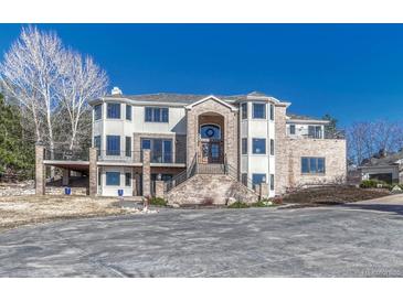 Elegant two-story home boasting a brick facade, balcony, and impressive entrance, set against a clear blue sky at 7672 S Ensenada Ct, Centennial, CO 80016