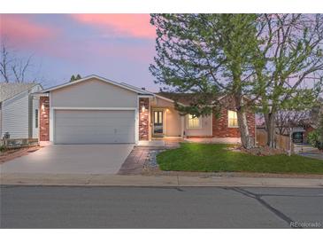Charming single-Gathering home featuring a manicured front lawn, brick accents, and an attached two-car garage at 8900 Iris Ct, Broomfield, CO 80021