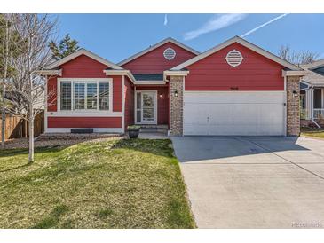 Charming red home with a well-maintained lawn, two-car garage and brick-accented entryway at 9408 High Cliffe St, Highlands Ranch, CO 80129