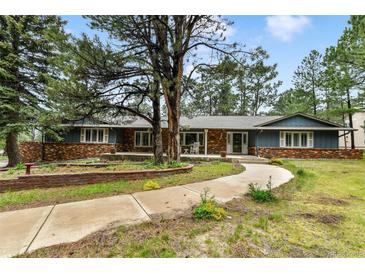 Charming home featuring blue siding, brick accents, a welcoming porch, and mature trees at 19070 White Fawn Dr, Monument, CO 80132