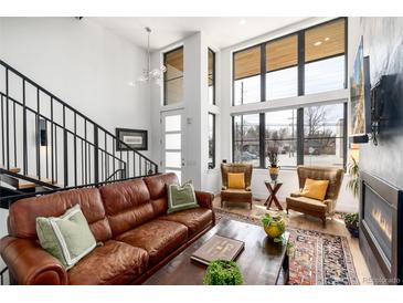 Bright living room featuring hardwood floors, a modern staircase, and large windows at 4243 E 8Th Ave, Denver, CO 80220