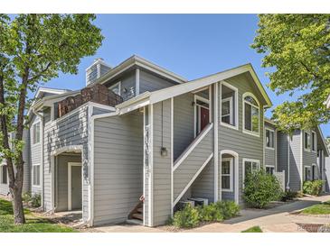 Inviting two-story condo with gray siding, red door, staircase entrance, and fresh green landscaping at 8500 E Jefferson # 3C, Denver, CO 80237