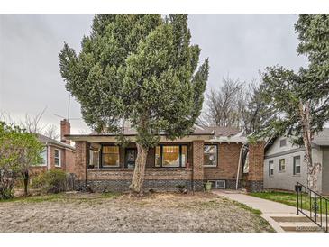 Charming brick home featuring a covered front porch and mature landscaping at 2866 Bellaire St, Denver, CO 80207