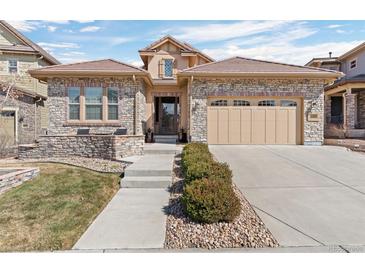 Charming home featuring a stone facade, tiled roof, well-maintained landscaping, and a two-car garage at 10662 Skydance Dr, Highlands Ranch, CO 80126