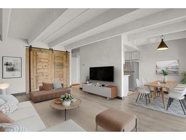 Bright living room featuring modern furniture, wood floors, a decorative sliding barn door, and an open concept to the kitchen at 100 S Clarkson St # 303, Denver, CO 80209