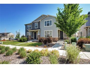 Inviting two-story townhome featuring stone accents, lush landscaping, and a well-maintained walkway at 952 Morning Glory Rd, Brighton, CO 80640