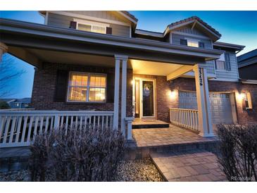 Charming brick home showcasing a welcoming front porch with classic white columns and manicured landscaping at 23426 E Ottawa Dr, Aurora, CO 80016
