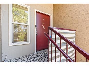 This apartment entrance features a red door, staircase with handrail, and adjacent window at 5300 E Cherry Creek South Dr # 124, Denver, CO 80246