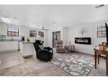 Bright living room features a fireplace, ceiling fan, and access to balcony at 10950 W Florida Ave # 303, Lakewood, CO 80232