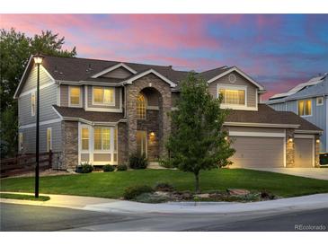 Charming two-story home featuring a brick facade, manicured lawn, and three-car garage at 6088 Rogers Cir, Arvada, CO 80403