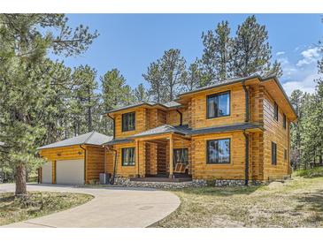 Two-story log home with a large attached garage and a circular driveway at 7350 Fremont Pl, Larkspur, CO 80118