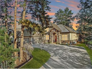 Two-story home with stone accents, three-car garage, and landscaped yard at 5224 Knobcone Dr, Castle Rock, CO 80108