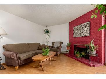 Living room with a vibrant painted fireplace, wood floors, and comfortable seating arrangement at 1390 Everett Ct # 220, Lakewood, CO 80215