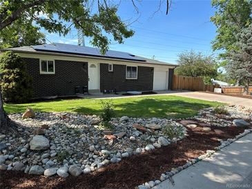 Charming brick home with a well-manicured lawn, rock garden and solar panels on the roof at 5585 W 51St Pl, Denver, CO 80212