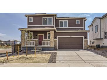 Two-story home with brown siding, brick accents, and a two-car garage on a sunny day at 798 Sawdust Dr, Brighton, CO 80601