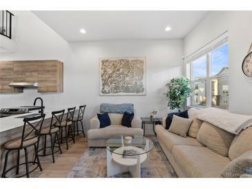 Open living area with modern sofas, coffee table, and large windows at 3553 W 63Rd Ave, Denver, CO 80221