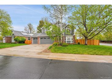 Beautiful two-story home with a gray exterior, brick accents, a well-manicured lawn, and a three car garage at 1101 Ridgeview Cir, Broomfield, CO 80020