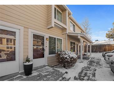 Tan exterior of townhome with snowy walkway and landscaping at 8979 Field St # 21, Broomfield, CO 80021