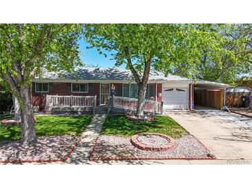 Charming brick home featuring a manicured lawn, mature trees, and a cozy front porch at 14157 E 26Th Ave, Aurora, CO 80011