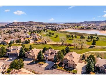 Stunning aerial view of homes nestled on a golf course community with a picturesque lake and mountain backdrop at 16611 Red Cliff Cir, Morrison, CO 80465