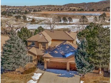 Inviting two-story home featuring a three car garage, a tile roof, and mature trees on a picturesque lot at 16611 Red Cliff Cir, Morrison, CO 80465