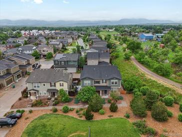 Expansive aerial view of a neighborhood showcasing well-maintained homes and lush green spaces, with mountains in the distance at 14823 W 70Th Dr # A, Arvada, CO 80007