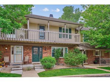 Charming two-story townhome featuring a brick facade, balcony, green door and a well-maintained front yard at 6880 E Appleton Cir, Centennial, CO 80112