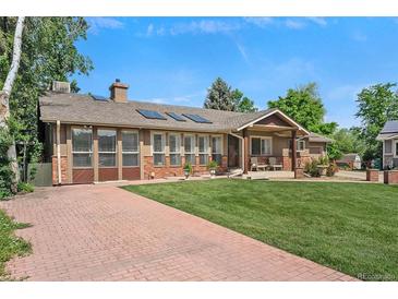 Inviting home featuring a brick and stucco facade, covered porch, and well-maintained front lawn at 6223 W Flora Pl, Denver, CO 80227