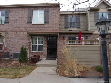 Charming townhome featuring a brick facade, covered entry, and well-maintained landscaping at 559 Alton Way # C, Denver, CO 80230