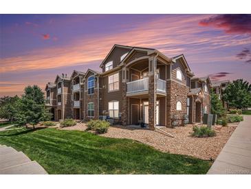 Beautiful multi-story condo building with stone accents, private balconies, and well-manicured lawn at 7440 S Blackhawk St # 14-208, Englewood, CO 80112
