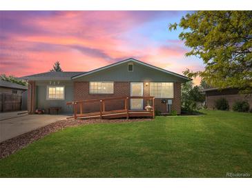 Charming brick home with a wooden ramp and well-maintained lawn against a beautiful sunset sky at 717 E 4Th Ave, Longmont, CO 80504
