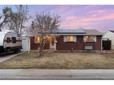 Charming single-story brick home featuring solar panels, a cozy porch swing, and a well-maintained lawn at 6903 W 52Nd Pl, Arvada, CO 80002