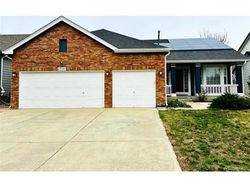 Charming brick home featuring a two-car garage and solar panels on the roof at 6596 Silverleaf Ave, Firestone, CO 80504