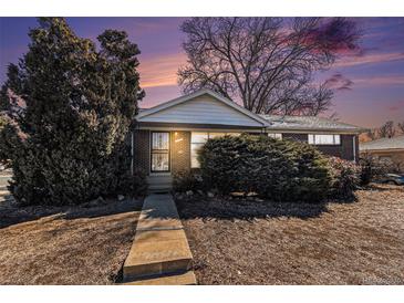 Charming single-story brick home with mature trees at dusk at 7232 Kalamath St, Denver, CO 80221