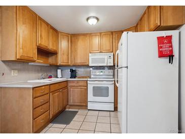 Cozy kitchen featuring wooden cabinets, neutral countertops, and essential appliances at 710 S Clinton St # 1A, Denver, CO 80247