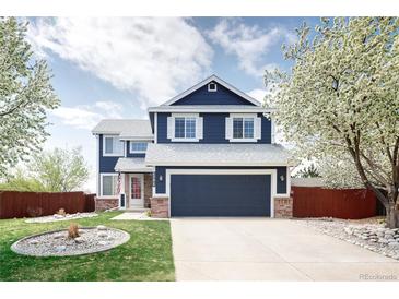 Charming two-story home with a well-maintained lawn, garden bed and a blue exterior and white trim at 21742 E Lehigh Pl, Aurora, CO 80018