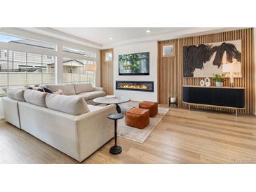 Comfortable living room featuring a fireplace, large windows, and a comfortable sectional sofa at 4408 Riviera Ct, Aurora, CO 80019