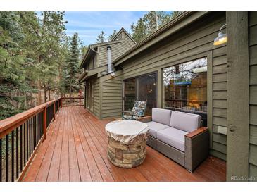 Inviting deck with a comfortable couch and a stone fire pit table perfect for outdoor gatherings and relaxation at 3065 Piney Ridge Rd, Evergreen, CO 80439