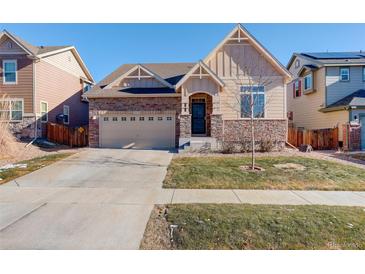 Two-story house with stone and siding, two-car garage, and landscaped yard at 10256 Olathe Way, Commerce City, CO 80022