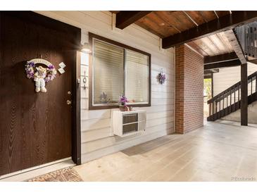 Charming entrance with a decorative wreath on a wood door and a window with a small air conditioning unit at 14806 E 2Nd Ave # 104G, Aurora, CO 80011