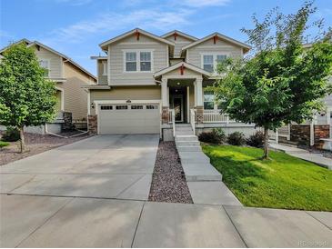 Charming two-story home with stone accents, a well-manicured lawn, and a wide driveway leading to a two-car garage at 14880 Chicago St, Parker, CO 80134