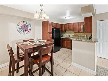 Bright kitchen featuring tile floors, dark cabinets, and a black refrigerator, open to the dining area at 430 Zang St # 4-103, Lakewood, CO 80228