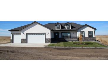 Charming home featuring a manicured lawn, stone accents, and an attached two-car garage at 56315 E 74Th Ave, Strasburg, CO 80136