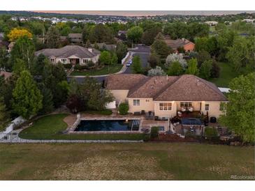 Expansive backyard featuring a pool, hot tub, covered patio and views of the manicured yard at 5653 Yank St, Arvada, CO 80002