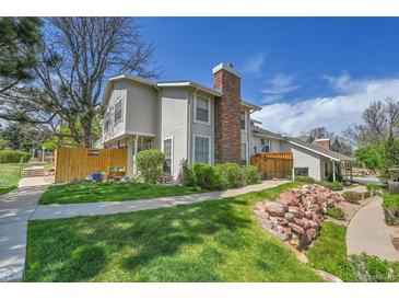 Charming exterior view of townhome with a brick chimney, green lawn, and well-maintained landscaping at 7077 S Knolls Way, Centennial, CO 80122